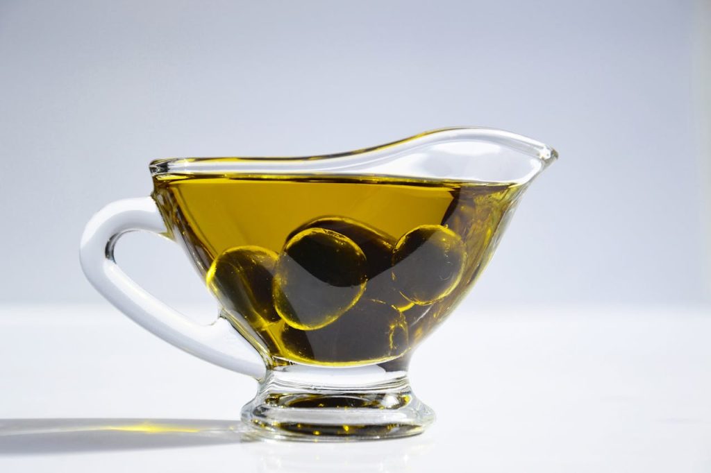 High-resolution image of a glass cup filled with olive oil and olives, ideal for culinary themes.